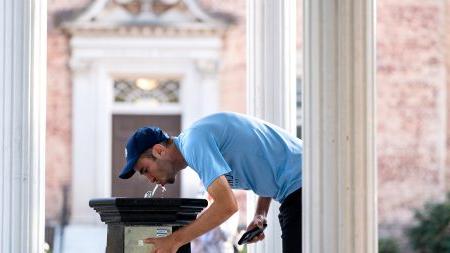 Student sipping from the Old Well on the first day of classes at UNC-Chapel Hill.